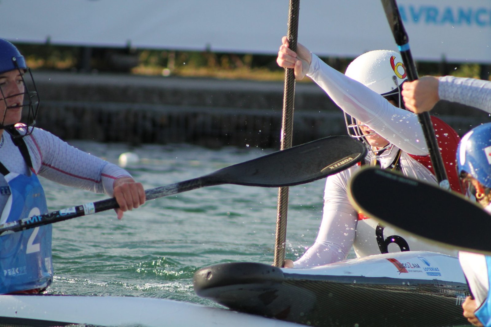 A Spanish kayak polo player challenges an opponent for the ball, paddles crossed, during the ECA 2025 European Championships in Avranches.